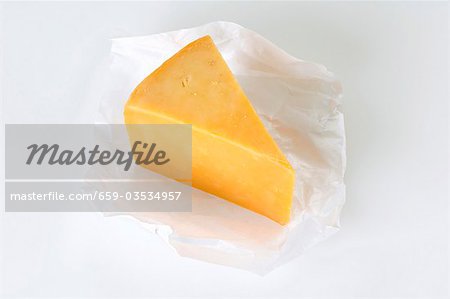 A piece of Cheddar cheese on paper