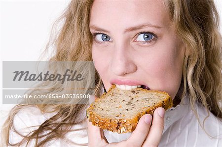 Young woman bitung into a slice of grannary bread