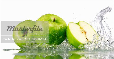 Pommes vertes, entières ou coupées en deux, avec des projections d'eau