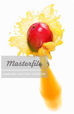 Mango juice splashing out of bottle