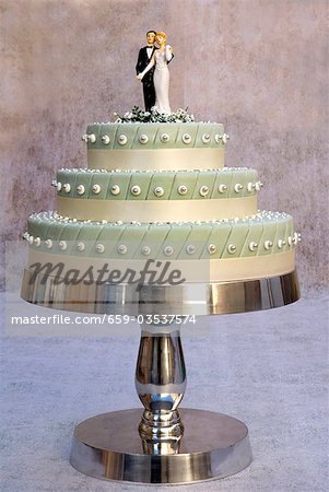 Three-tiered wedding cake with bride and groom cake toppers