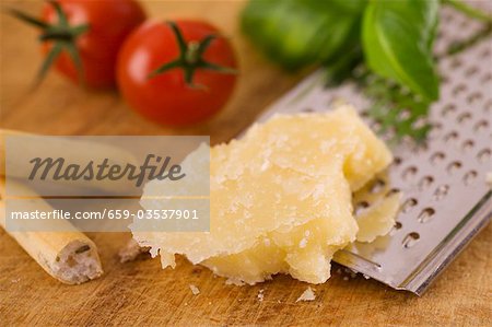 Parmesan with grater, grissini, tomatoes and basil