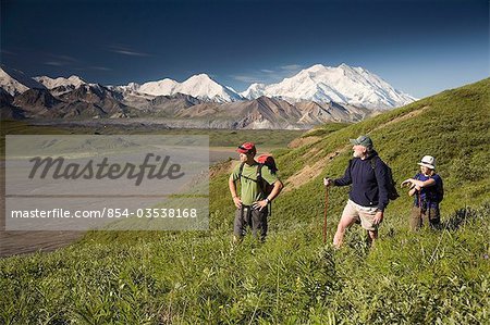 Family of three day hikers man and young couple at Grassy Pass with MtMcKinley in background Denali NP Alaska