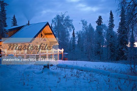 Log Cabin in the woods decorated with Christmas lights at twilight near Fairbanks, Alaska during Winter