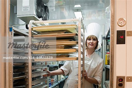 Chef féminin en marche dans le congélateur en cuisine commerciale