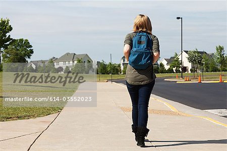 Female high school student walking along pavement