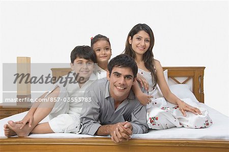 Famille souriant sur le lit
