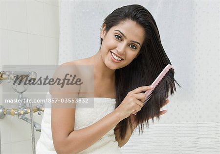 Femme peignant les cheveux dans la salle de bain, Gurgaon, Haryana, Inde