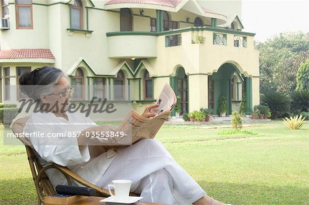 Femme lisant un journal dans une pelouse, New Delhi, Inde