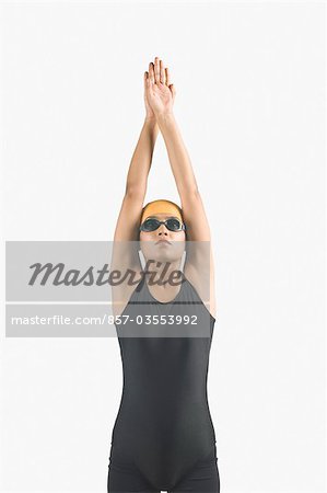 Young woman wearing swimwear and standing with her arms raised