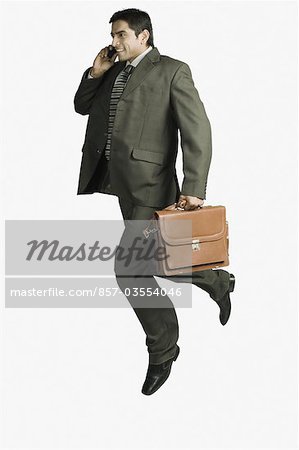 Businessman talking on a mobile phone and jumping