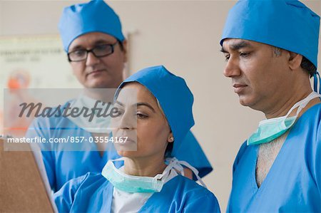 Drei Chirurgen diskutieren eine Krankenakte, Gurgaon, Haryana, Indien