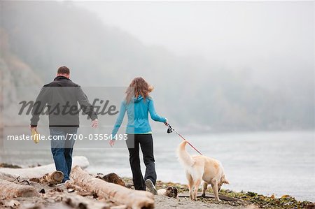 Couple Walking Dog at Puget Sound in Discovery Park, Seattle, Washington, USA