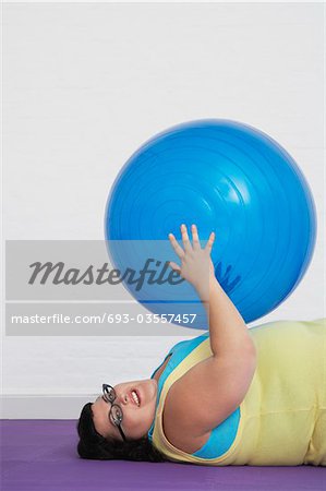 Übergewichtige Frau hält gymnastikball liegend