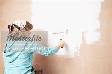 Mur intérieur femme peinture avec le rouleau à peinture