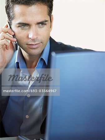 Businessman Using Cell Phone and Laptop Indoors