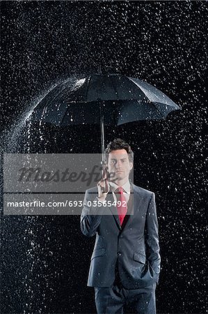 Businessman standing under sturdy Umbrella, hand in pocket