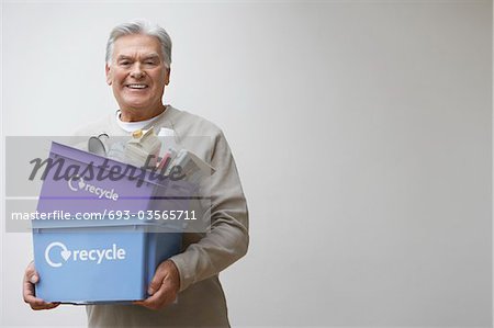 Middle-aged man holding recycling containers, smiling