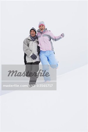 Couple qui descend la colline enneigée, vue d'angle faible