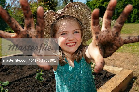 Junges Mädchen im Garten mit schlammigen Händen