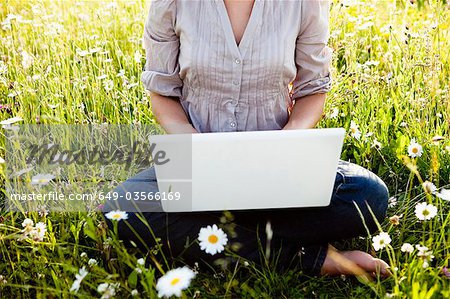 Woman with Laptop sitting in wild meadow