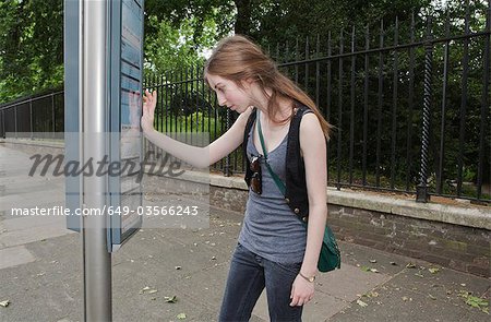 Young Woman looking at Busfahrplan