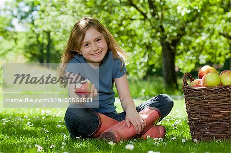 Girl in meadow, eating apple