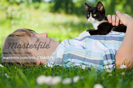 Boy in meadow hugging a cat