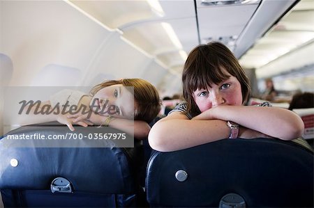 Two Little Girls Looking Over Seats on Airplane