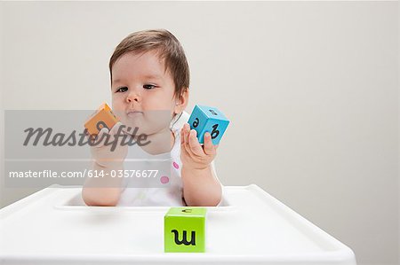 Baby boy sitting in highchair with wooden alphabet blocks