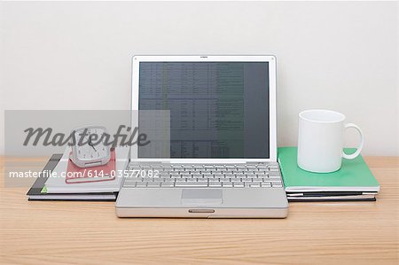 Laptop with alarm clock and mug