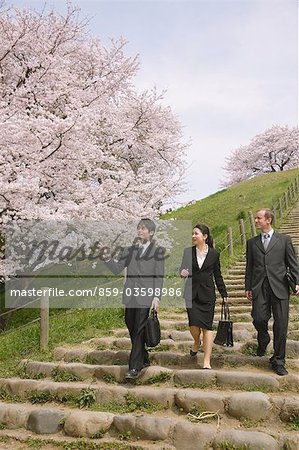 Businesspeople Walking in Park While Conversing