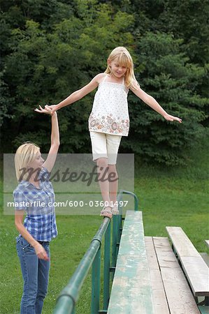 Girl Balancing on Railing while Mother Holds her Hand