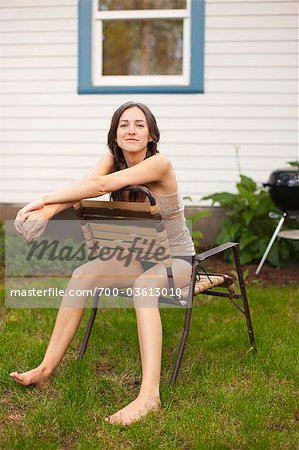 Woman Sitting Backwards on Lawn Chair in Backyard