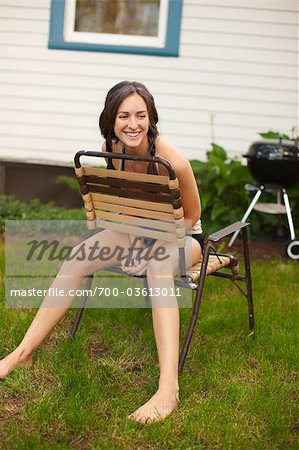 Woman Sitting Backwards on Lawn Chair in Backyard