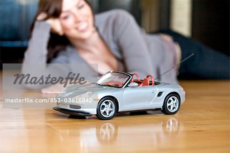 Femme allongée sur le sol et en regardant voiture jouet