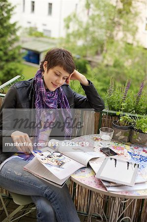 Jeune femme lisant magazine sur balcon