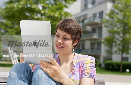 Young woman using iPad on a bench