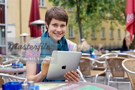 Young woman using iPad at an outdoor cafe
