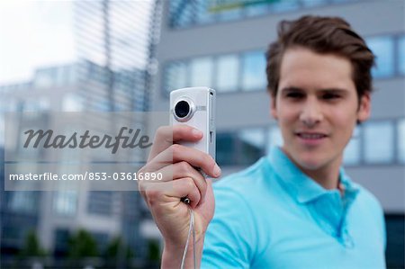 Young man with smartphone in front of office building