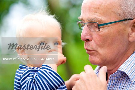 Grandfather carrying toddler outdoors, portrait