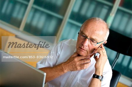 Homme senior sur téléphone portable au bureau à domicile