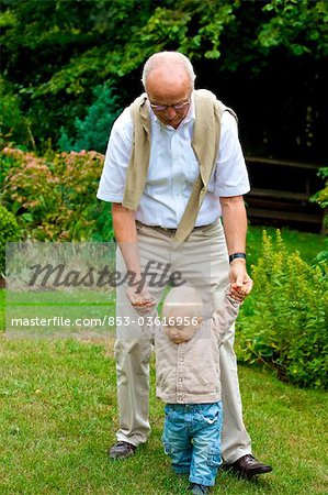 Grandfather helping toddler to walk