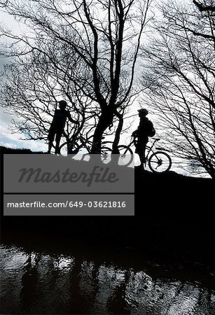 Silhouette couple biking in countryside