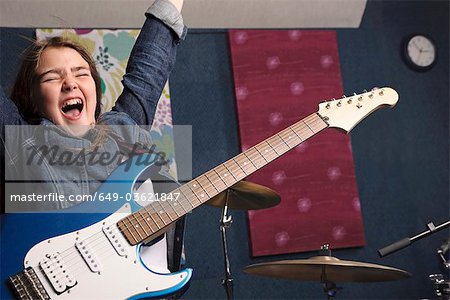 Young girl playing guitar in studio