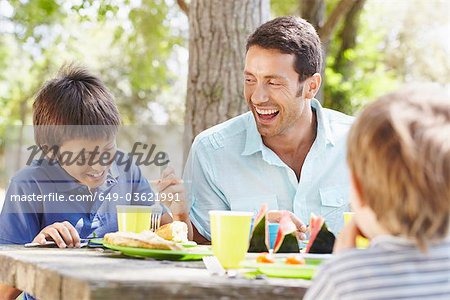 Happy father with 2 boys having a picnic