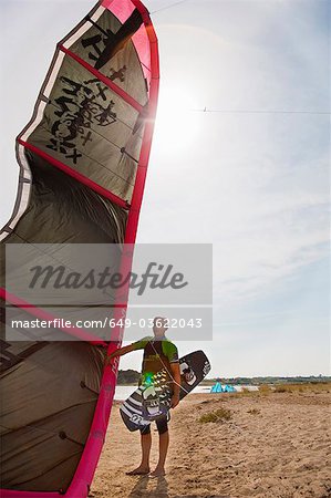 Kitesurfer holding kite and board