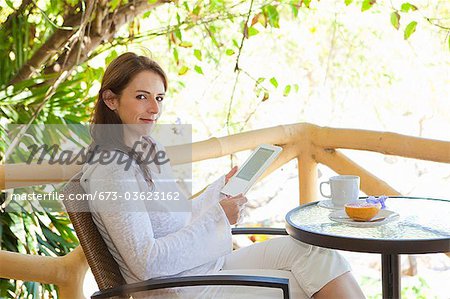 femme lisant des e-book sur le balcon