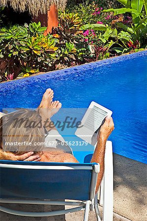 man reading e-book on chaise outdoors
