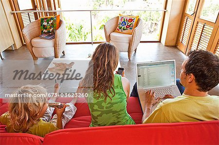 parents à l'aide d'ordinateur portable avec l'enfant sur le canapé